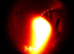 10. Dezember 2015: Das erste Plasma in Wendelstein 7-X. Es bestand aus Helium, dauerte eine Zehntel Sekunde und erreichte eine Temperatur von rund einer Million Grad Celsius. (Eingefärbtes Schwarz-Weiß-Foto)