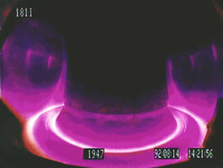 Blick in das Plasma des Fusionsexperiments ASDEX Upgrade. Zu sehen ist die leuchtende Randschicht des Plasmas, die auf die Divertorplatten am Boden des Gefäßes gelenkt wird. Durch den Divertor werden Verunreinigungen aus dem Plasma entfernt.