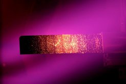 The image shows a W7-X target during high heat flux loading with 10 MW/m² in GLADIS. The spotted glow of the surface at about 1000 °C is caused by the fibre structure of the CFC material.