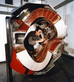 Ein Teilstück des Stellaratorexperimentes Wendelstein 7-AS wird montiert: Die verwundenen Magnetfeldspulen werden zusammen mit Abstützkeilen in die äußere Stützschale eingepaßt.