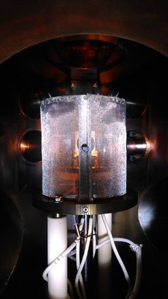 Target chamber of SIESTA with heated sample. The sample is located within a wire cage to minimize the emission of secondary electrons, as these would compromise the measurement of the impinging ion current.