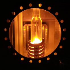 Blick in ROST mit der Induktionsspule, die das doppelwandige Glasrohr umgibt in dem ein Wolframzylinder glüht.
