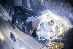 Ein Techniker arbeitet im Plasmagefäß des IPP-Stellarators Wendelstein 7-X an den Kacheln.